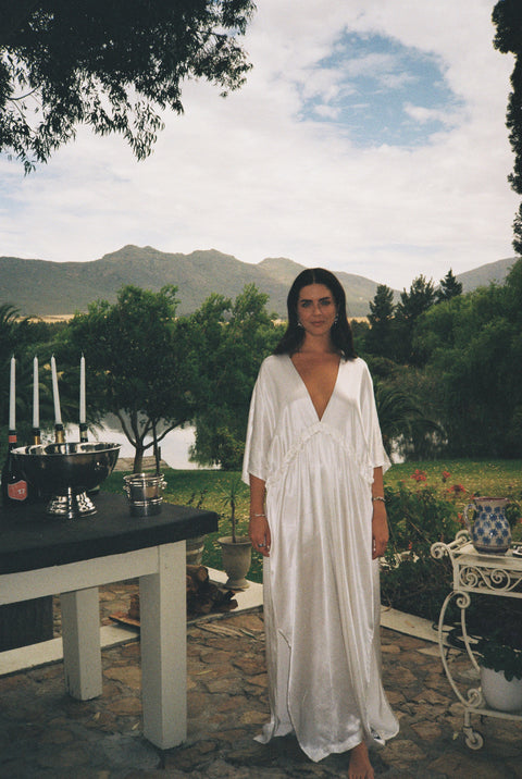 Woman in a white dress standing outdoors with mountains in the background